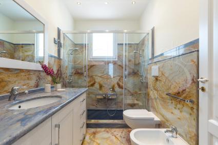 The bathroom with shower is characterized by refined marble